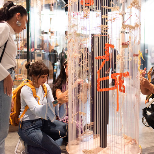 Two women in the Burke Museum look at an interactive display on weaving
