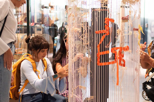 Two women in the Burke Museum look at an interactive display on weaving